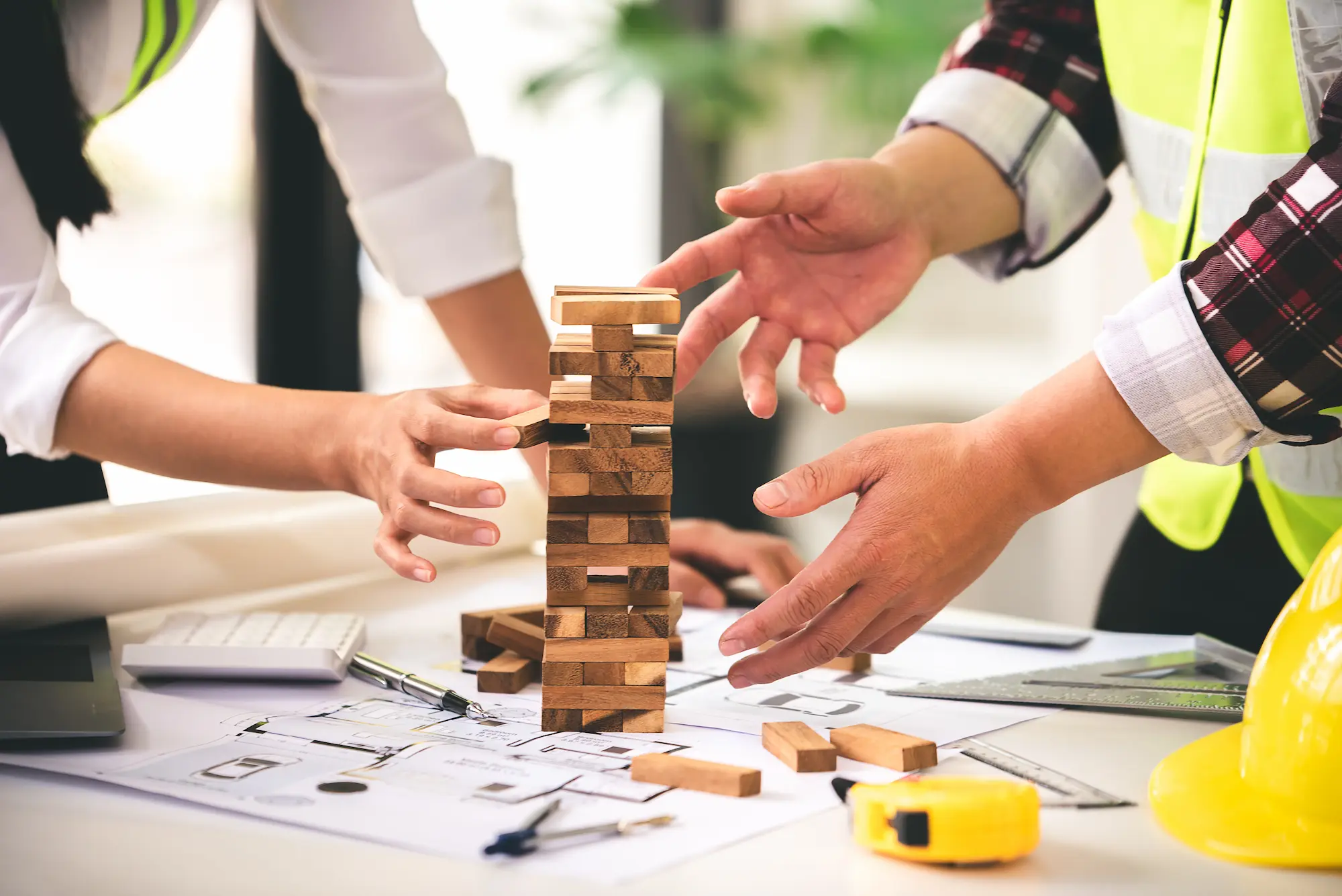architect and construction worker protecting a jenga tower